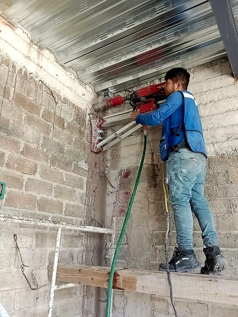 Técnico perforando un muro de block con broca diamantada para anclaje